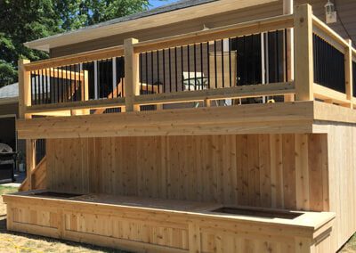 custom cedar deck build with black metal balusters and built in flower planters