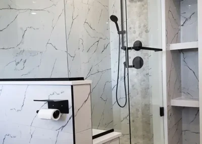 bathtub replaced with a custom walk-in marble shower with contrasting black showerhead and a large marble bench