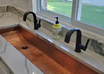 quartzite countertops with large copper trough sink and double black vanity faucets