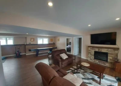 cozy, rustic country home basement entertainment room with stacked stone fireplace